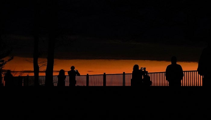 People look out towards Lake Erie during a total solar eclipse in Dunkirk, New York, REUTERS