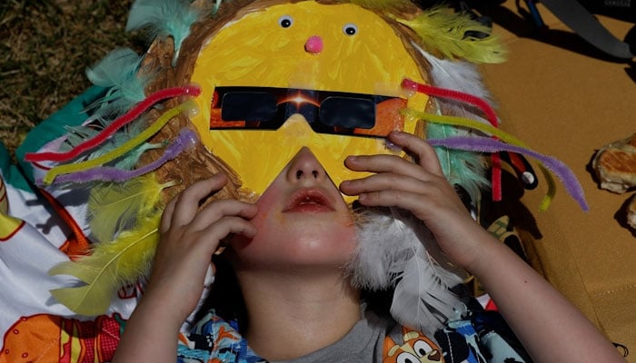 A child wears a mask with solar eclipse glasses in Carbondale. REUTERS