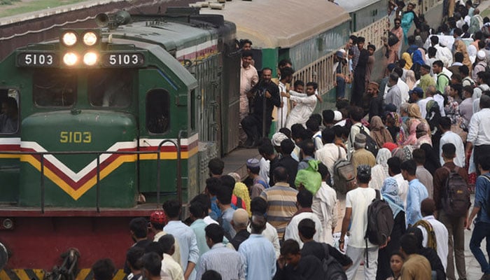 People board a train at a railway station as they return home ahead of Eid in Lahore on July 7, 2022. — AFP