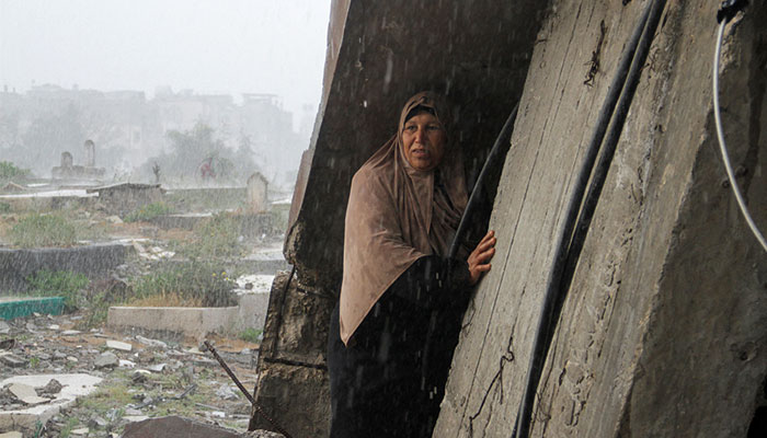 A woman shelters from the rain as Palestinians visit the graves of people who were killed by Israeli onslaught on the day of Eid al-Fitr, in Gaza Strip, April 10, 2024. — Reuters