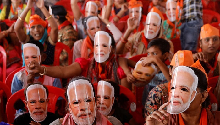Supporters of Indias Prime Minister Narendra Modi wear masks of his face, as they attend an election campaign rally in Meerut, India, March 31, 2024. — Reuters