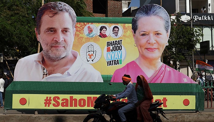 A couple on a motorcycle rides past a banner with the pictures of Rahul Gandhi and Sonia Gandhi, senior leaders of Indias main opposition Congress party, on a road during Rahuls 66-day long Bharat Jodo Nyay Yatra, or Unite India Justice March, in Jhalod town, Gujarat state, India, March 7, 2024. — Reuters