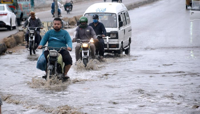 Vehicles passing through rain water at Korangi Road, Karachi on April 14, 2024. — APP
