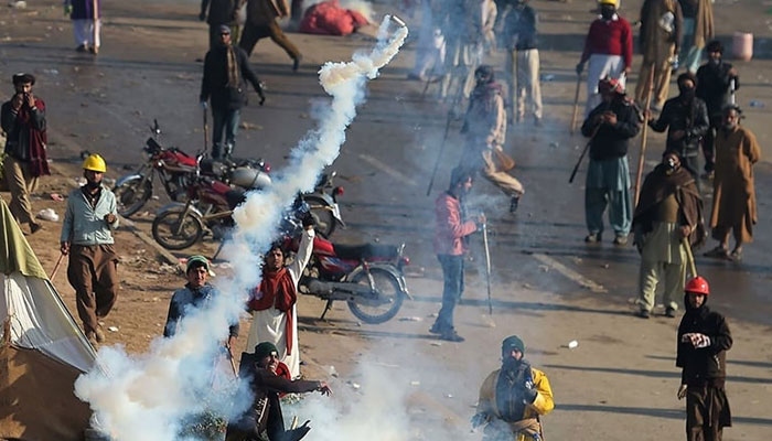 A protester throws a tear gas shell back towards police during a clash in Islamabad on Nov 25, 2017. ─ AFP