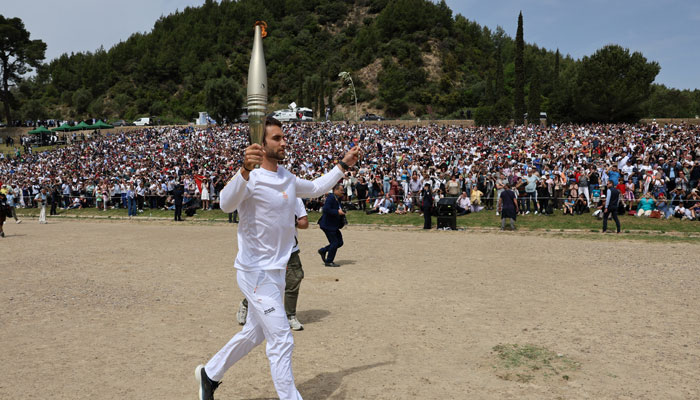 The first torchbearer Greek rower Stefanos Ntouskos, carries the touch during the start of the torch relay after the flame lighting ceremony for the Paris 2024 Olympics. — Reuters