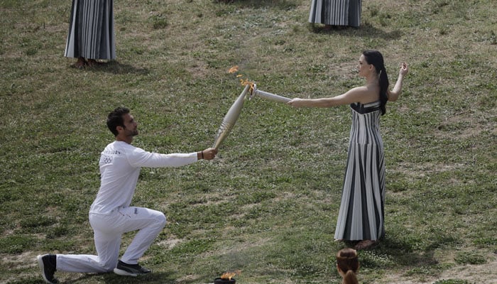 Greek actress Mary Mina, playing the role of High Priestess, passes the flame to the first torchbearer, Greek rower Stefanos Ntouskos, during the Olympic Flame lighting ceremony for the Paris 2024 Olympics. — Reuters