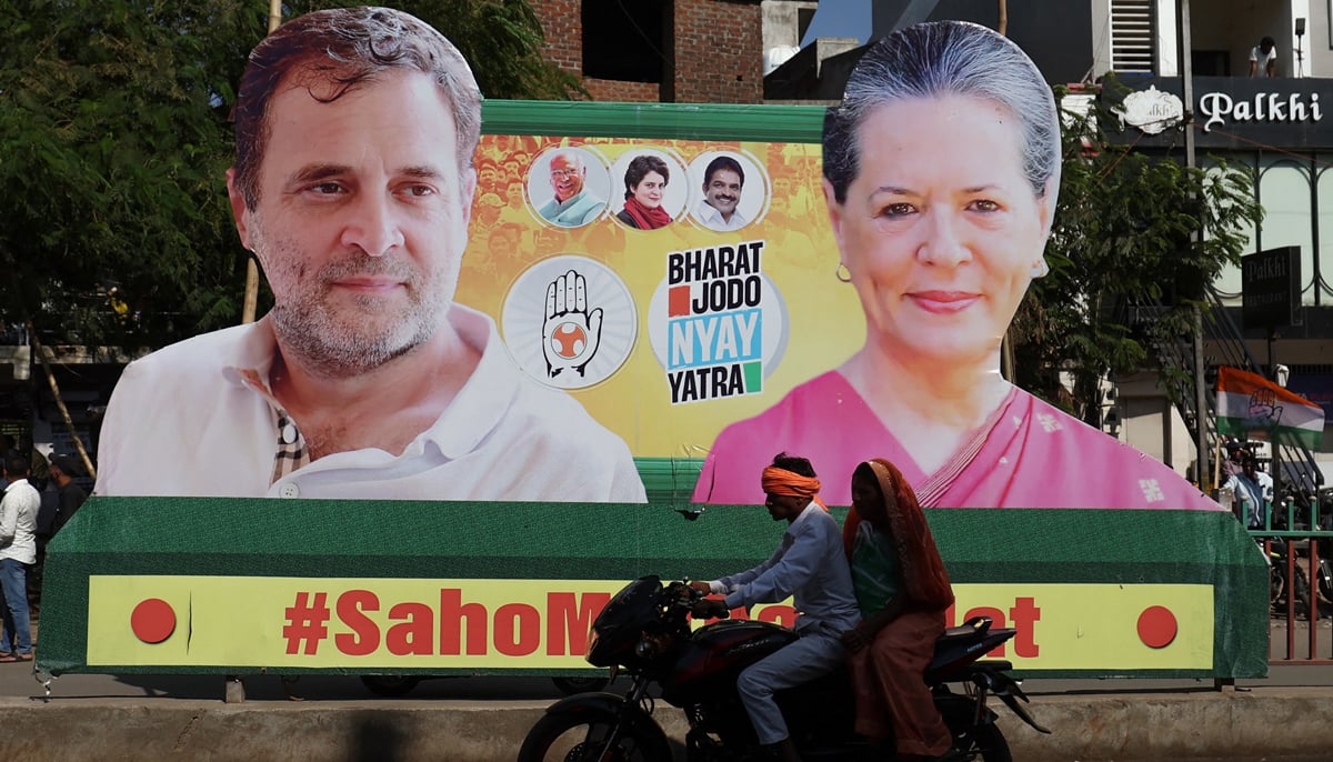 A couple on a motorcycle rides past a banner with the pictures of Rahul Gandhi and Sonia Gandhi, senior leaders of Indias main opposition party, Indian National Congress, on a road during Rahuls 66-day long Bharat Jodo Nyay Yatra, or Unite India Justice March, in Jhalod town, Gujarat state, India, March 7, 2024. — Reuters