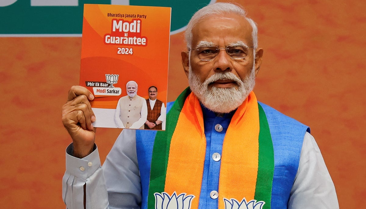 Indian Prime Minister Narendra Modi displays a copy of the ruling Bharatiya Janata Partys election manifesto for the general election, in New Delhi, India, April 14, 2024. — Reuters