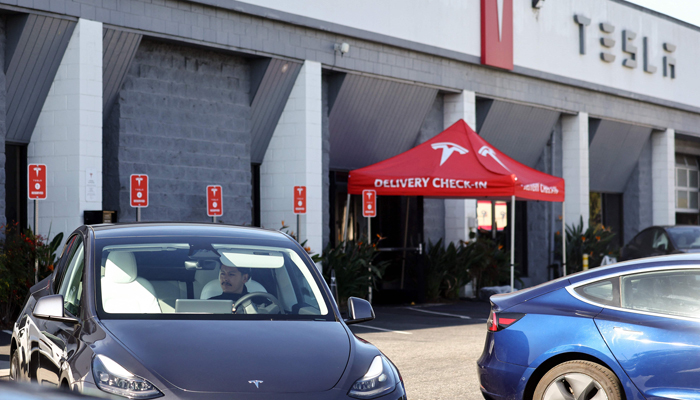 An employee prepares to park a Tesla electric car at a Tesla dealership on January 16, 2024, in Burbank, California.  - AFP