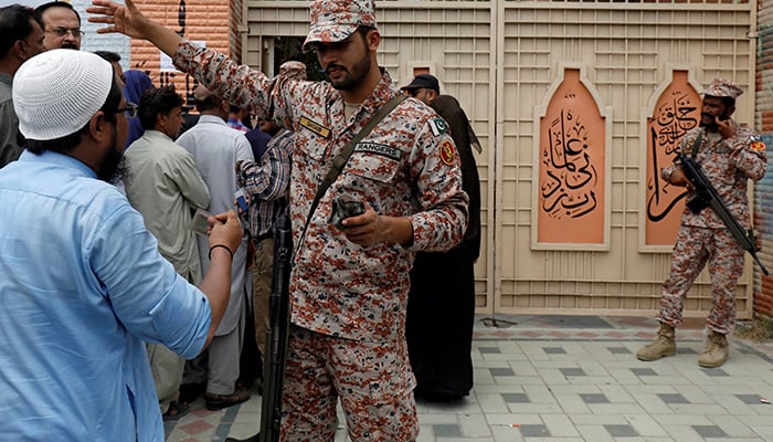 Ranger helps an electoral worker, who along with others gather to collect election materials, ahead of general election in Karachi, Pakistan July 24, 2018. Photo: Reuters