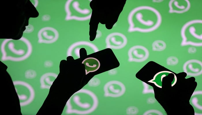Men pose with smartphones in front of displayed Whatsapp logo in this illustration September 14, 2017.— Reuters