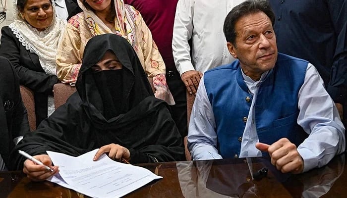 PTI Chairman Imran Khan (right) along with his wife Bushra Bibi who is signing surety bonds for bail in various cases, at a registrar office in the High court, in Lahore on July 17, 2023. — AFP