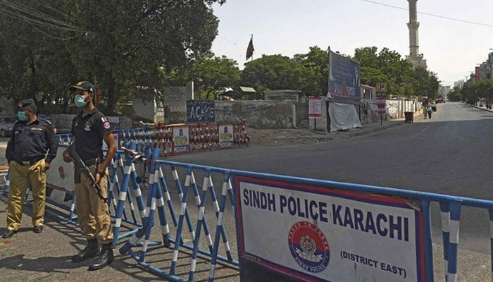 Police personnel stand guard at a road checkpoint in Karachi. — AFP/File