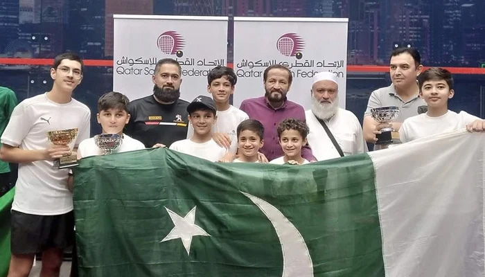 Pakistani squash players and officials holding national flag during Qatar Junior Squash Championship in Doha in this undated photo. — Facebook/KPSquashAssociation