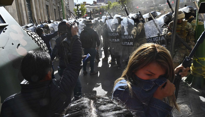 A woman walks away from tear gas fired by military troops outside the Quemado Palace at Plaza Murillo in La Paz on June 26, 2024. — AFP