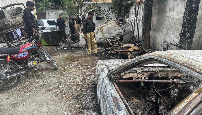 Policemen inspect the burned vehicles at a police station in the Madyan area of Swat Valley on June 21, 2024. —AFP