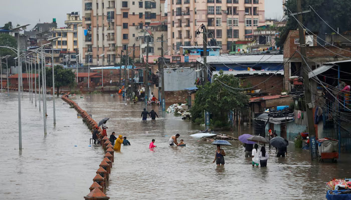 People walk along a flooded road along the bank of overflowing Bagmati river following heavy rains, in Kathmandu, Nepal August 8, 2023. — Reuters