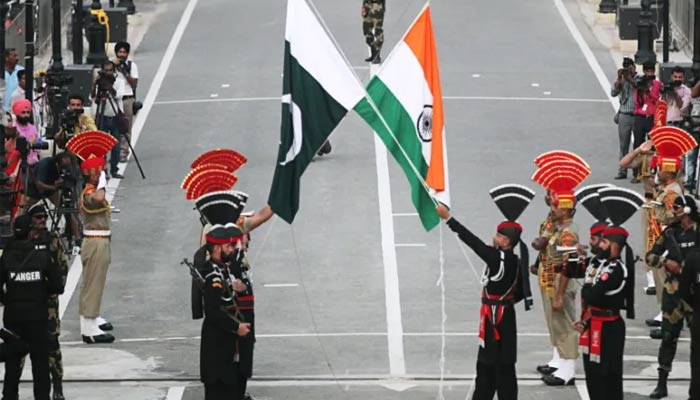 Pakistani Rangers in black uniforms and Indian Border Security Force (BSF) personnel lower their national flags during parade on Pakistans Independence Day at the Wagah border. — Reuters/File