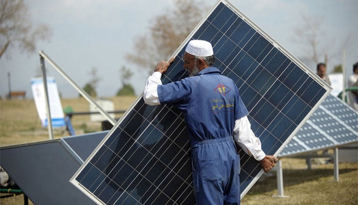 A Pakistani company employee arranges a solar panel during a marketing demonstration in a park in Islamabad. — AFP/File