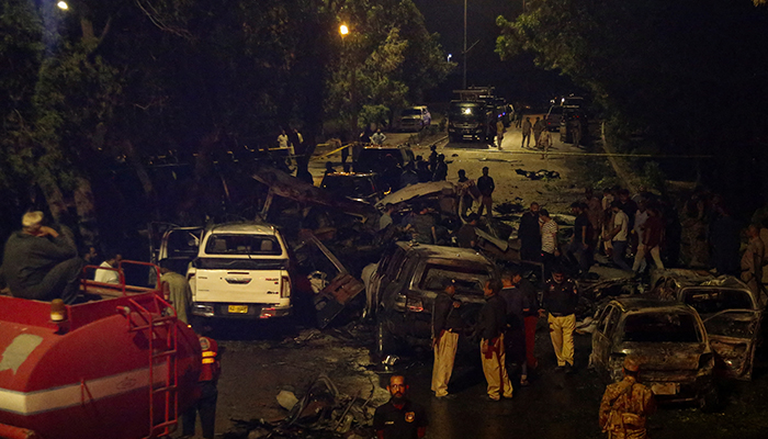 Police officers and paramilitary soldiers gather near the wreckage of vehicles after an explosion near Jinnah International Airport in Karachi, on October 6, 2024. — Reuters