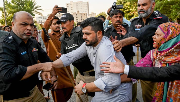 Police personnel detain PTI supporters whilst they protest to demand the release of former prime minister Imran Khan, in Karachi on October 18, 2024. — AFP