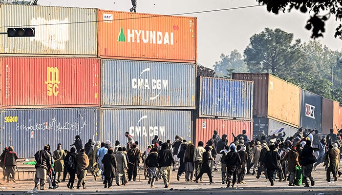 Supporters of PTI throw stones at paramilitary soldiers on top of the shipping containers during a protest demanding the release of former prime minister Imran Khan, at the Red Zone area in Islamabad on November 26, 2024. — AFP