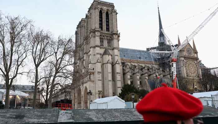 A woman wearing a red beret walks pas near the Notre-Dame de Paris Cathedral, which was ravaged by a fire in 2019, before the reopening ceremonies in Paris, France on December 6, 2024. — Reuters
