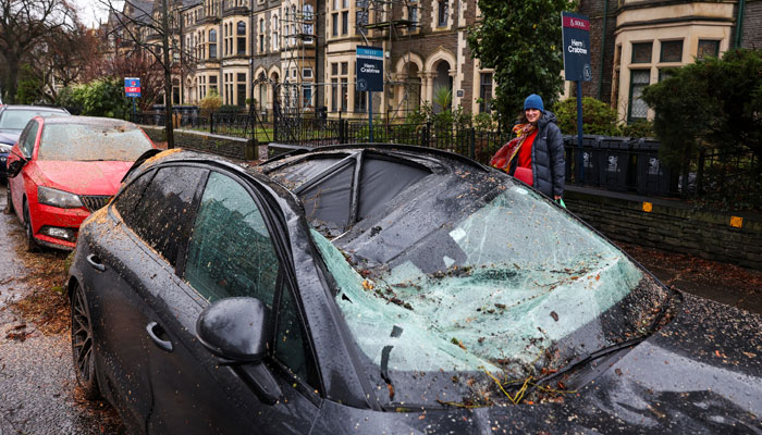 A person stands next to a car damaged by a fallen tree, after Storm Darragh hit the country in Penarth, Wales, Britain, December 7, 2024. — Reuters