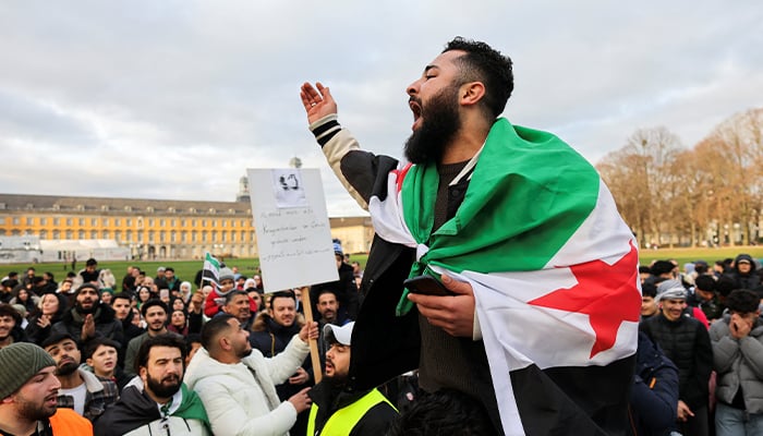 A man draped in a Syrian opposition flag reacts, as people gather on the streets, after Syrian rebels announced that they have ousted Syrias Bashar al-Assad, in Bonn, Germany December 8, 2024. — Reuters