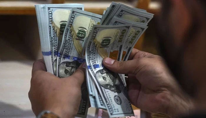 A currency changer counting $100 bills. — AFP/File