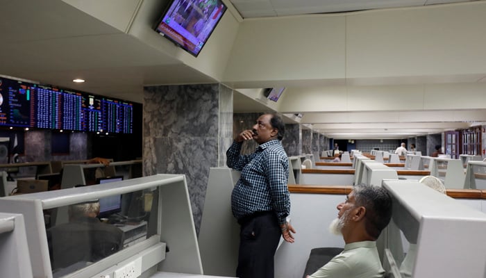 Stock brokers monitor news on a television screen at a stall, during a trading session at the Pakistan Stock Exchange, in Karachi, July 3, 2023. — Reuters