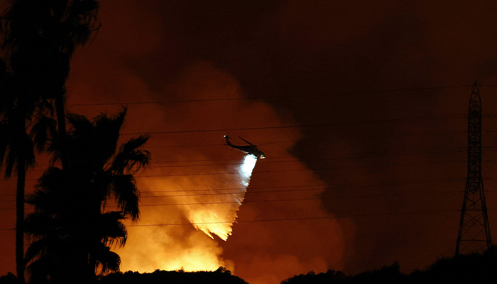 A firefighting helicopter drops water as the Palisades Fire burns toward the Mandeville Canyon neighborhood on January 10, 2025 in Los Angeles, California. — AFP