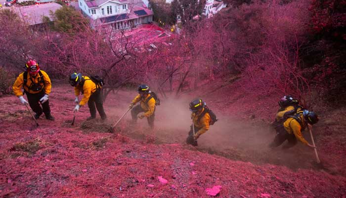 Firefighters work to clear a firebreak on a hillside covered with retardant as the Palisades Fire, one of several simultaneous blazes that have ripped across Los Angeles County, burns in Mandeville Canyon, a neighborhood of Los Angeles, California, US, January 12, 2025. — Reuters