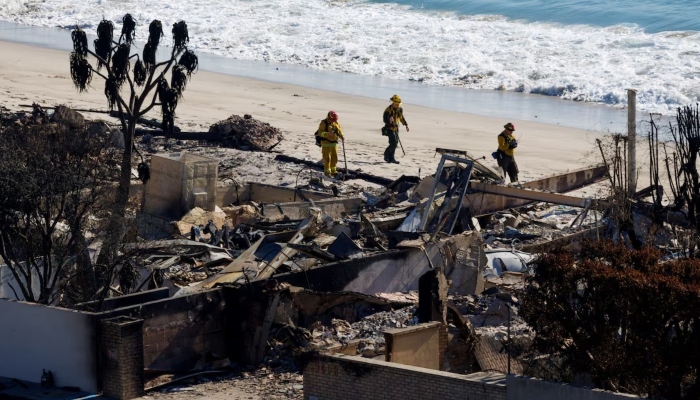 Firefighters walk next to the remains of beachfront houses that burnt down in the Palisades Fire, in Malibu, California, US, January 16, 2025. — Reuters