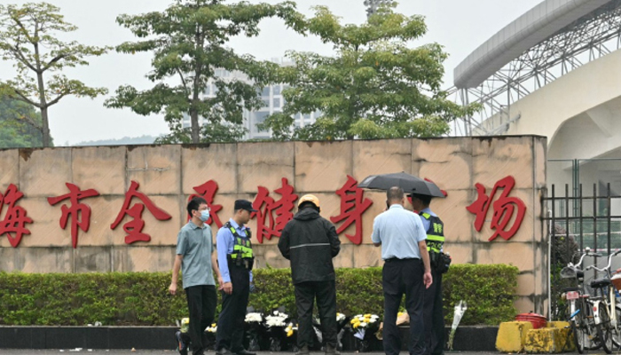 A delivery man (C) lays online orders of flower bouquets at a makeshift memorial outside the Zhuhai Sports Centre in Zhuhai in south Chinas Guangdong province after 35 people were killed when a man drove a car into a crowd in one of the countrys deadliest mass-casualty events in years. — AFP/File
