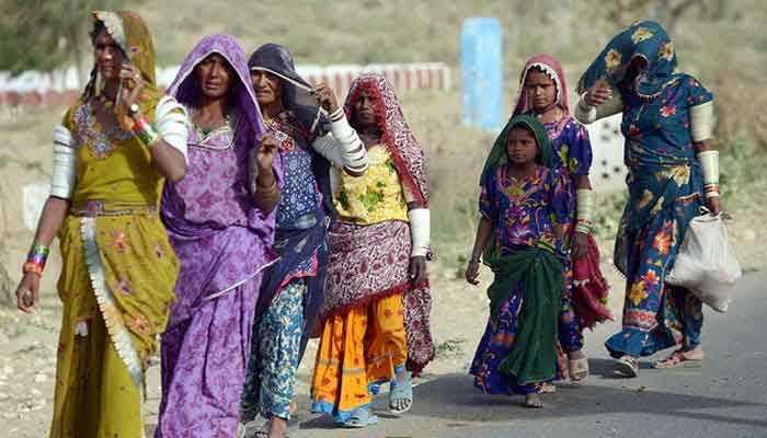 Pakistani women walk alongside the road in Mithi, the capital of Tharparkar district, some 300 kilometres from Karachi. — AFP