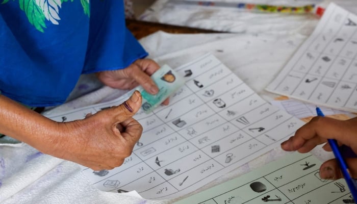 A voter with an ink mark on the thumb goes through paperwork to cast a vote during the general election in Karachi, on February 8, 2024. — Reuters