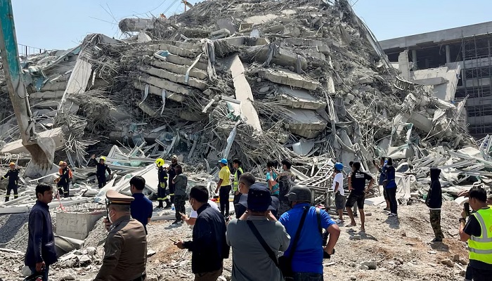 Rescue personnel stand near a building that collapsed in Bangkok. — Reuters