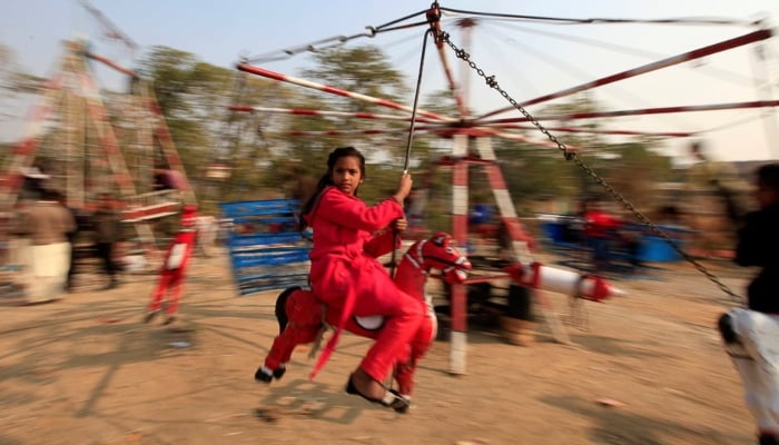 A girl rides on a makeshift merry go round on Christmas Day in Islamabad. — Reuters