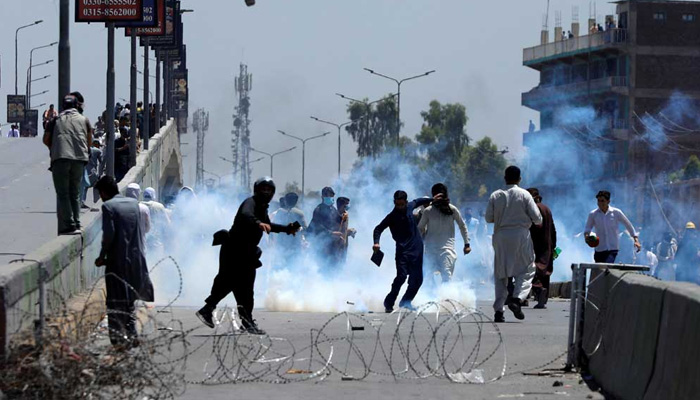 Supporters of PTI founder Imran Khan throw stones towards police during a protest against Khans arrest, in Peshawar on May 10, 2023. — Reuters