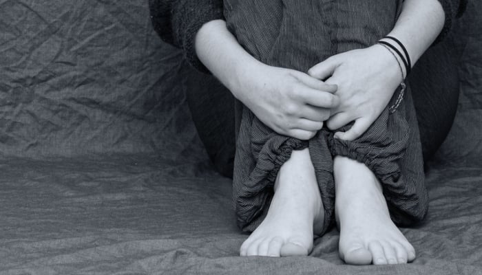 This representational image shows a person sitting with her hands wrapped around the legs. — Pixabay
