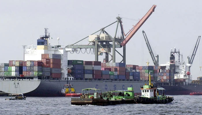 Vessels pass by a container ships being loaded with cargo at Karachi port. — AFP/File