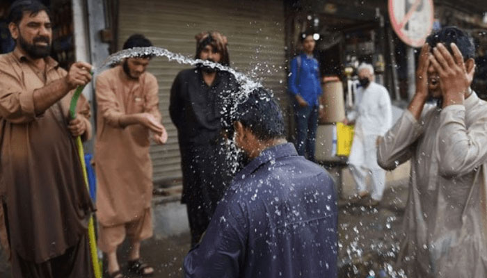 People spray each other with water as temperatures rise in Karachi. — AFP/File