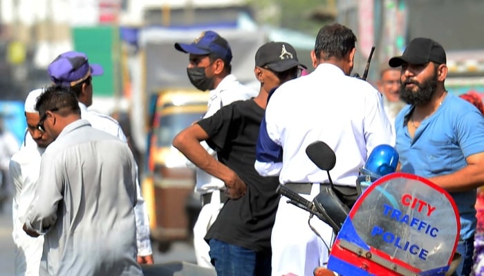 Traffic police officials charge a challan upon violating the traffic rules, at Saddar area in Karachi on Tuesday, April 15, 2025. — PPI