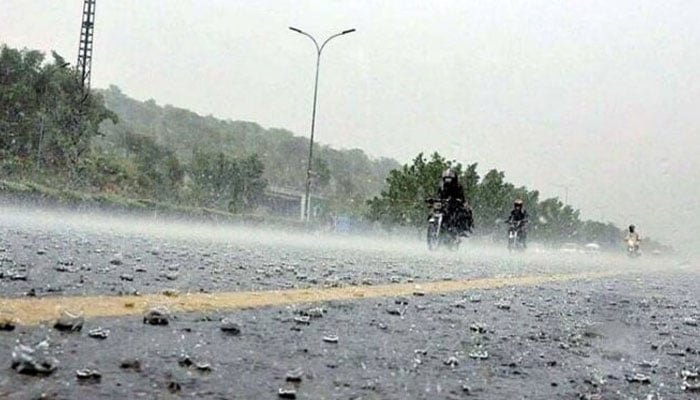 This undated photo shows motorcyclists moving on a road during hailstorm. — APP/File