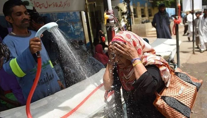 A volunteer showers a woman with water during a heat wave. — AFP/File