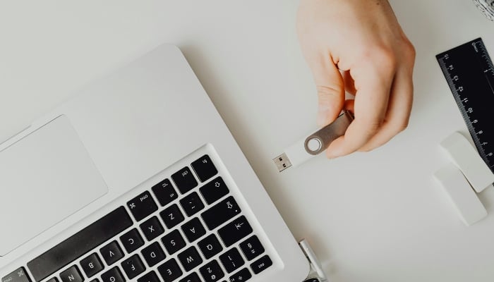 Representative image shows a person plugging a USB drive into a laptop. — Pexels