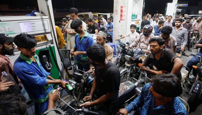 People wait their turn to get fuel at a petrol station, in Karachi. — Reuters/File