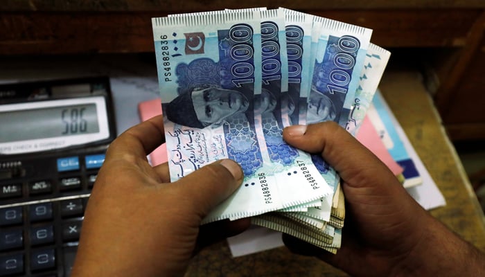 A trader counts Pakistani rupee notes at a currency exchange booth in Peshawar, December 3, 2018. — Reuters