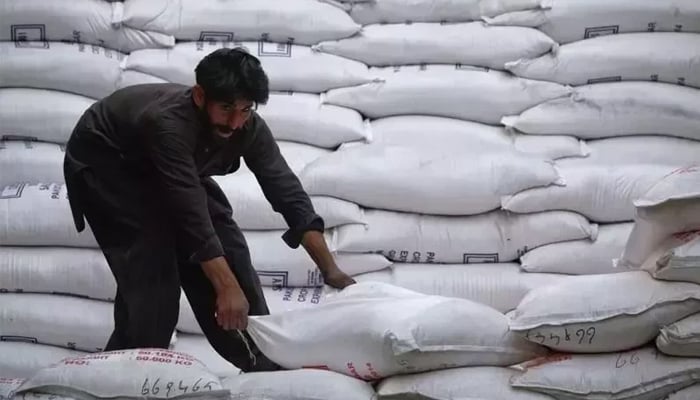 A labourer unloads sacks of sugar from a supply truck at the main wholesale market in Karachi. — Reuters/ File